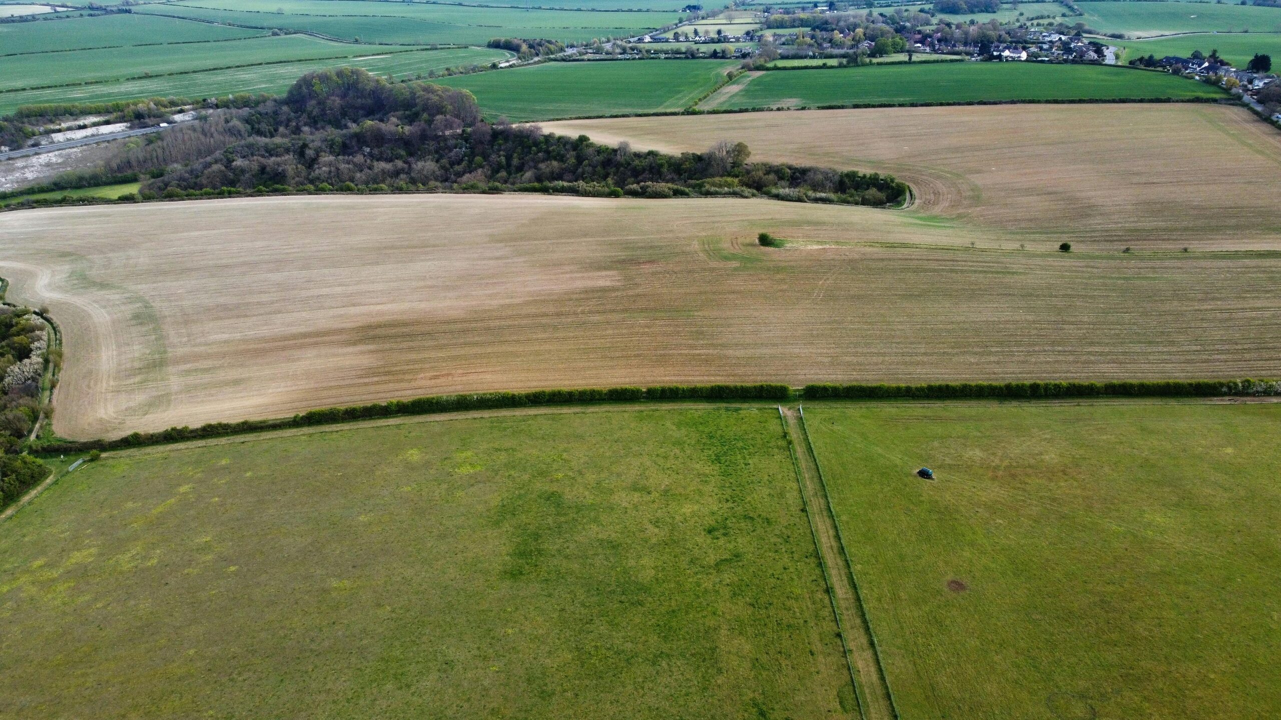 Aerial shot of lush green and brown agricultural fields in Sharpenhoe, England